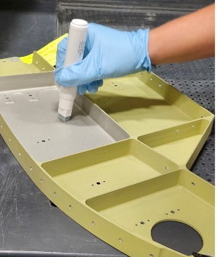 A gloved hand applying surface treatment to an aircraft structure